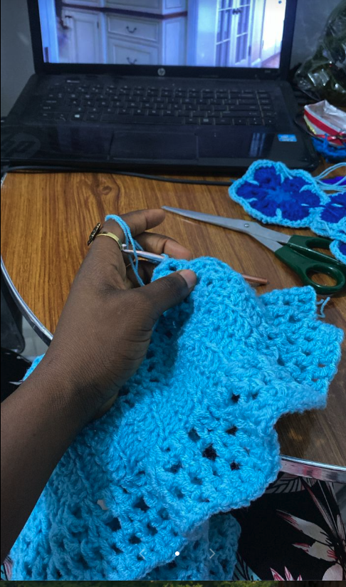Hands crafting blue crochet pieces